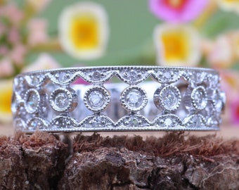 May include: A silver band ring with a delicate design featuring small round diamonds set in a scalloped pattern.