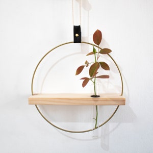 May include: A gold metal hoop with a wooden shelf and a glass test tube for holding a single stem of dried foliage. The hoop is suspended from the ceiling with a black leather strap and twine.