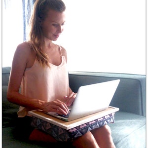 Pu&ograve; includere: Una donna &egrave; seduta su un divano e usa un laptop su un tavolino da divano. Il tavolino da divano &egrave; rivestito in tessuto rosa e grigio con un motivo. Il laptop &egrave; bianco e ha una tastiera nera.