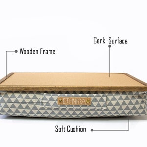 Pu&ograve; includere: Un cuscino con motivo grigio e bianco con una cornice in legno e una superficie in sughero. Il cuscino ha una maniglia e il testo "ETHNICA" sul davanti.