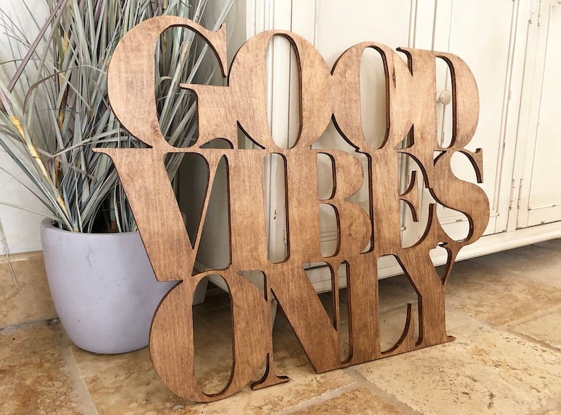 May include: Wooden sign with the words "Good Vibes Only" in a decorative font. The sign is brown and has a distressed look.