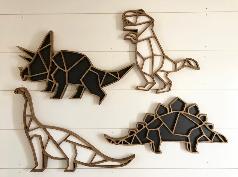 May include: Four wooden dinosaur wall decorations in a geometric style. The dinosaurs are painted black and white and are arranged in a row on a white wall.