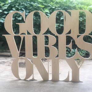 May include: Wooden sign with the words "Good Vibes Only" cut out in a decorative font.