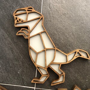 May include: A wooden dinosaur wall decor with a white geometric design. The dinosaur is standing on its hind legs with its tail curled up.