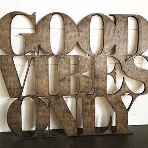 May include: Wooden sign with the words "Good Vibes Only" in a brown stain finish.