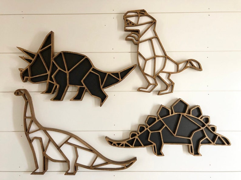 May include: Four wooden dinosaur wall decorations in a geometric style. The dinosaurs are painted black and white and are arranged in a row on a white wall.