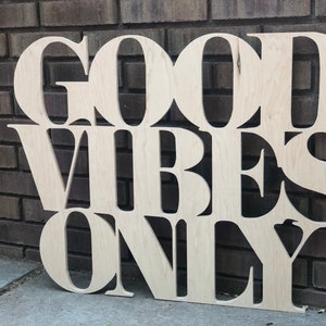 May include: Wooden sign with the words "Good Vibes Only" in large, stylized letters.