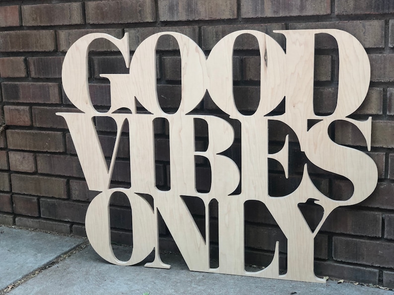 May include: Wooden sign with the words "Good Vibes Only" in large, stylized letters.