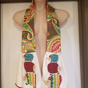 May include: A white kitchen towel with a red, green, and yellow paisley design. The towel has three embroidered hedgehogs on each side. The hedgehogs are stacked on top of each other and have a flower on their heads.