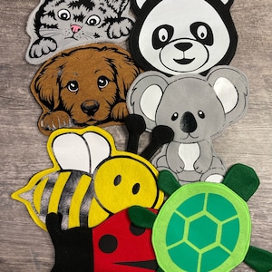 Peut inclure: Un ensemble de marionnettes en feutre d'animaux et d'insectes. L'ensemble comprend un chat, un panda, un koala, une abeille, une coccinelle et une tortue. Les marionnettes sont toutes de couleurs vives et ont des visages amicaux.