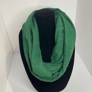 Puede incluir: Una bufanda infinita verde con un patrón de espiga. La bufanda se muestra en un maniquí negro.