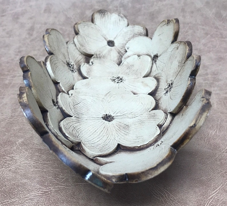 May include: A decorative bowl with a floral design. The bowl is shaped like a flower with multiple petals. The petals are white with dark brown edges and a dark brown center. The bowl is made of a ceramic material.