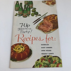 May include: A vintage 7-Up cookbook with a red and white cover featuring a photo of a ham, a salad, and a gelatin mold. The text on the cover reads "7-Up goes to a Party! Recipes for: Barbecues, Guest Dinners, Open Houses, Holiday Events."