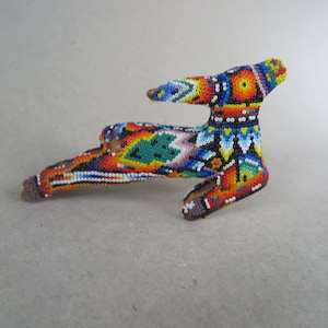 May include: A handcrafted, beaded deer figurine. The deer is adorned with a vibrant array of colorful beads, including red, orange, yellow, green, blue, and white. The figurine has a wooden base and is a unique decorative item.