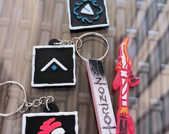 May include: Keychains featuring various designs, including a stylized arrow, a character profile, and a weapon, all in vibrant colors. One keychain has the word "Horizon" printed on it. Each keychain has a silver keyring.