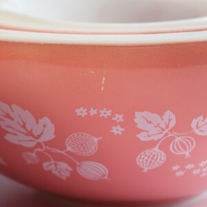 May include: A set of three pink mixing bowls with a white gooseberry pattern. The bowls are nested inside each other.