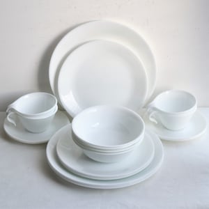 May include: A set of white Corelle dinnerware, including plates, bowls, and cups. The set is made of durable, chip-resistant, and microwave-safe material.