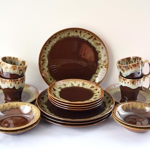 Puede incluir: Un juego completo de vajilla de cerámica marrón vintage. El juego incluye platos grandes, platos más pequeños, cuencos, platillos y tazas. Los bordes de los platos, cuencos y tazas tienen un diseño moteado de color marrón claro y crema.