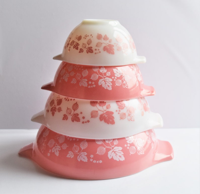 May include: A set of four nesting mixing bowls with a pink and white gooseberry pattern. The bowls are stacked in a pyramid shape.