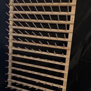 May include: Wooden yarn holder with multiple dowels for storing yarn. The holder is made of natural wood and has a rustic look.