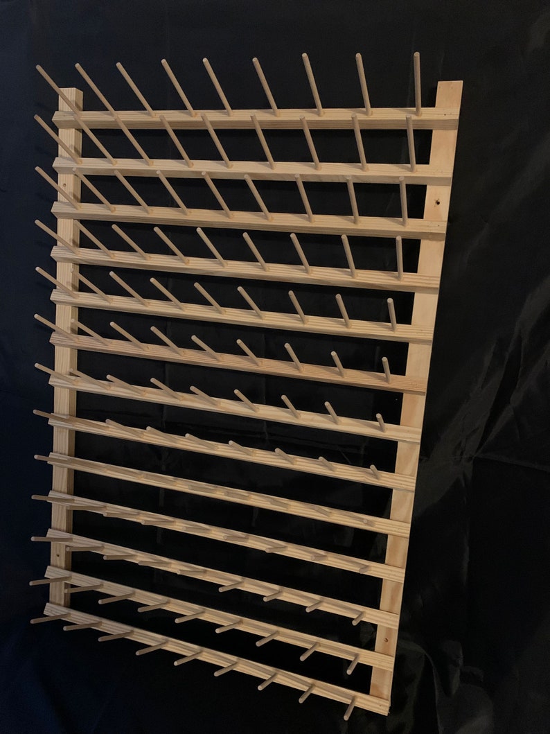 May include: Wooden yarn holder with multiple dowels for storing yarn. The holder is made of natural wood and has a rustic look.