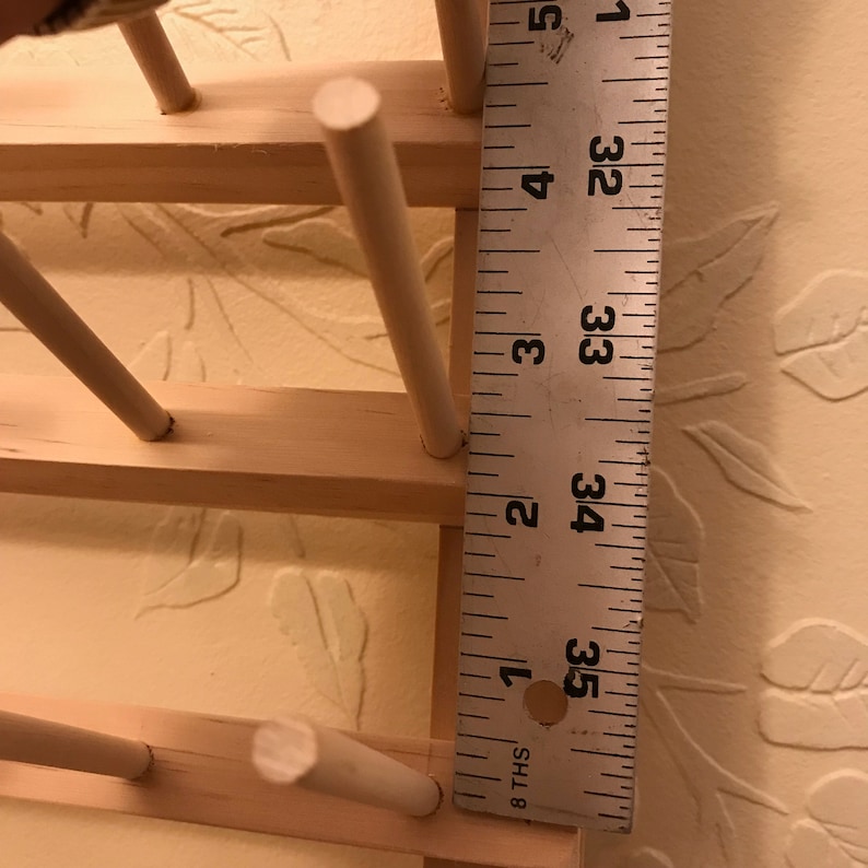 May include: A wooden rack with white dowels for holding jewelry or other small items. The rack is 3 1/2 inches tall.