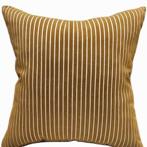 May include: Mustard-colored decorative pillow with vertical white stripes. The pillow has a square shape with a slightly rounded edge. The striped pattern is evenly spaced across the pillow's surface.