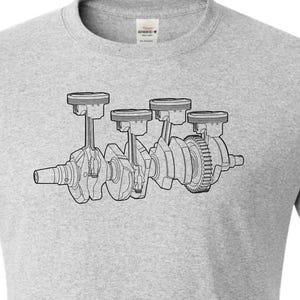 Puede incluir: Camiseta gris ceniza con una ilustración en blanco y negro de un cigüeñal de motor. El diseño incluye pistones, bielas y un engranaje. La camiseta es de cuello redondo.