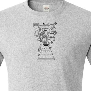 May include: Ash grey t-shirt with a black line drawing of a rocket engine on the front. The text "Ash Grey" is printed at the bottom of the shirt. The shirt has short sleeves and a crew neck.
