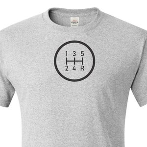 May include: Ash grey t-shirt with a black and white graphic of a 5-speed manual transmission gear shift pattern.