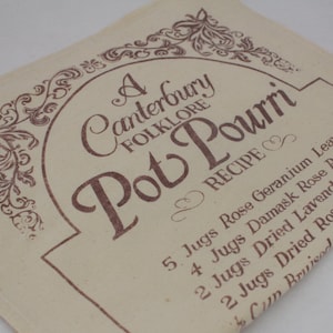 May include: A white fabric tea towel with brown text that reads "A Canterbury Folklore Pot Pourri Recipe" and lists the ingredients for a potpourri recipe. The ingredients include rose geranium leaves, damask rose petals, dried lavender flowers, and dried rosemary leaves.