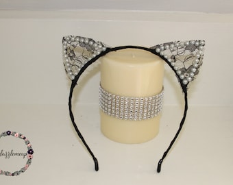 May include: Black headband with two black lace cat ears trimmed with white pearls.