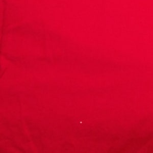 May include: Solid red fabric with a slight texture. The fabric is smooth and appears to be a soft material.
