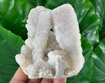 May include: White and light pink crystal cluster with a rough, textured surface. The cluster is shaped like a small mountain or rock formation.