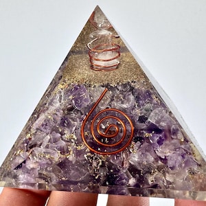 May include: A clear pyramid-shaped resin art piece with amethyst crystals and gold flakes. Copper wire spirals and coils are embedded within the pyramid. The pyramid is held by a hand.