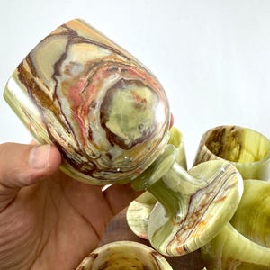 May include: Set of six green, brown and white marble drinking glasses. The glasses have a unique swirling pattern and are perfect for serving drinks.