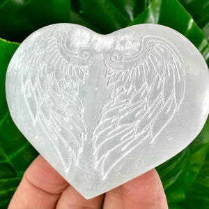 May include: White selenite heart with etched angel wings. The heart is smooth and polished.