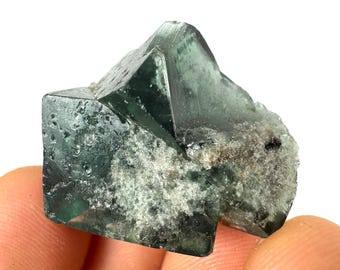 May include: A green fluorite crystal with a rough, textured surface. The crystal is a cluster of several intergrown crystals.