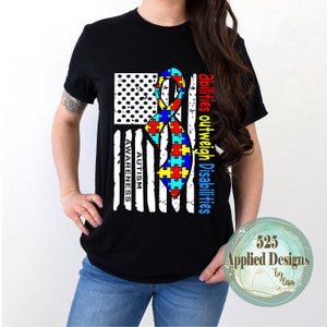 May include: Black t-shirt with an American flag design featuring a puzzle piece ribbon. The text "Autism Awareness" is on the flag and "Abilities outweigh Disabilities" is on the side of the flag.