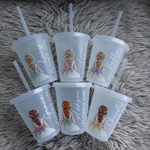 May include: Six clear plastic cups with lids and straws. Each cup features a floral girl illustration and a name: Lucy, Leah, Bella, Grace, Addison, and Christy. The text "FLOWER GIRL" is printed vertically on each cup.