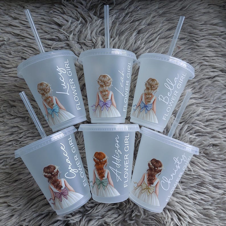 May include: Six clear plastic cups with lids and straws. Each cup features a floral girl illustration and a name: Lucy, Leah, Bella, Grace, Addison, and Christy. The text "FLOWER GIRL" is printed vertically on each cup.