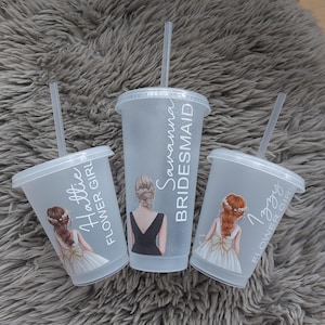May include: Three clear plastic tumblers with lids and straws. Each tumbler has a different name and title: "Hattie Flower Girl", "Savanna Bridesmaid", and "Izzy Flower Girl". The tumblers feature illustrations of women in formal attire.