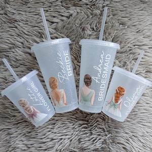May include: Four clear plastic tumblers with lids and straws. Each tumbler has a different name and role: "Beckie Bride", "Andrea Bridesmaid", "Olivia Flower Girl", and "Lottie Flower Girl". The tumblers have illustrations of women in wedding attire.