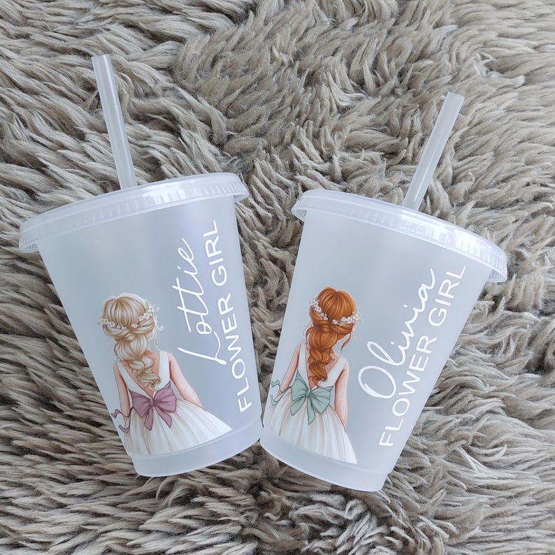 May include: Two clear plastic cups with lids and straws. Each cup features a drawing of a flower girl in a white dress with a bow. One cup says "Lottie Flower Girl" and the other says "Olivia Flower Girl".
