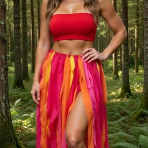 May include: A woman wearing a red tube top, a colorful skirt with orange, pink, and yellow ribbons, and a leaf crown. The outfit is set against a backdrop of a forest with tall trees.