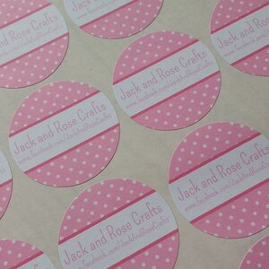 May include: A sheet of pink and white polka dot stickers. Each sticker is circular with a white band featuring the text "Jack and Rose Crafts" and a website address. The stickers are laid out on a pale surface.