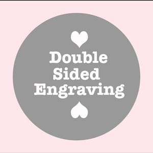 Puede incluir: Un círculo gris con corazones blancos y el texto "Double Sided Engraving" en blanco.