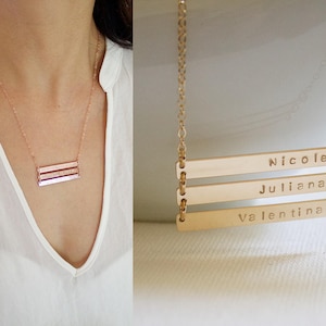 Puede incluir: Collar de oro con tres barras horizontales grabadas con los nombres "Nicole", "Juliana" y "Valentina".