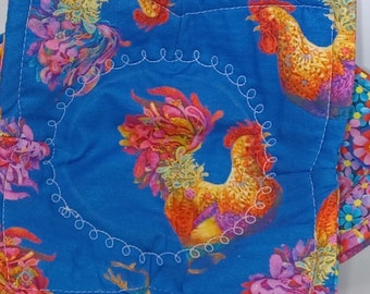 May include: A set of four blue fabric pot holders with a white stitched border. Each pot holder features a colorful rooster design with floral accents.