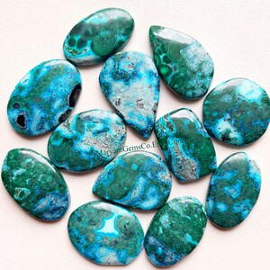 May include: Ten green and blue chrysocolla cabochons with a marbled pattern. The cabochons are oval shaped and have a smooth, polished surface.